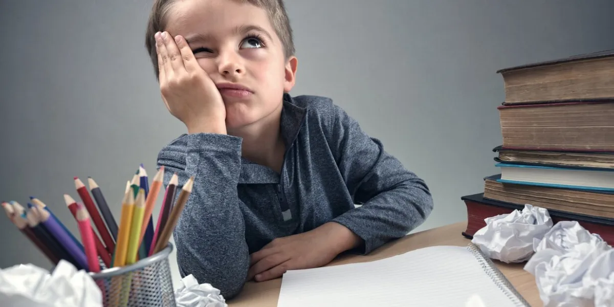 thinking child bored, frustrated and fed up doing his homework