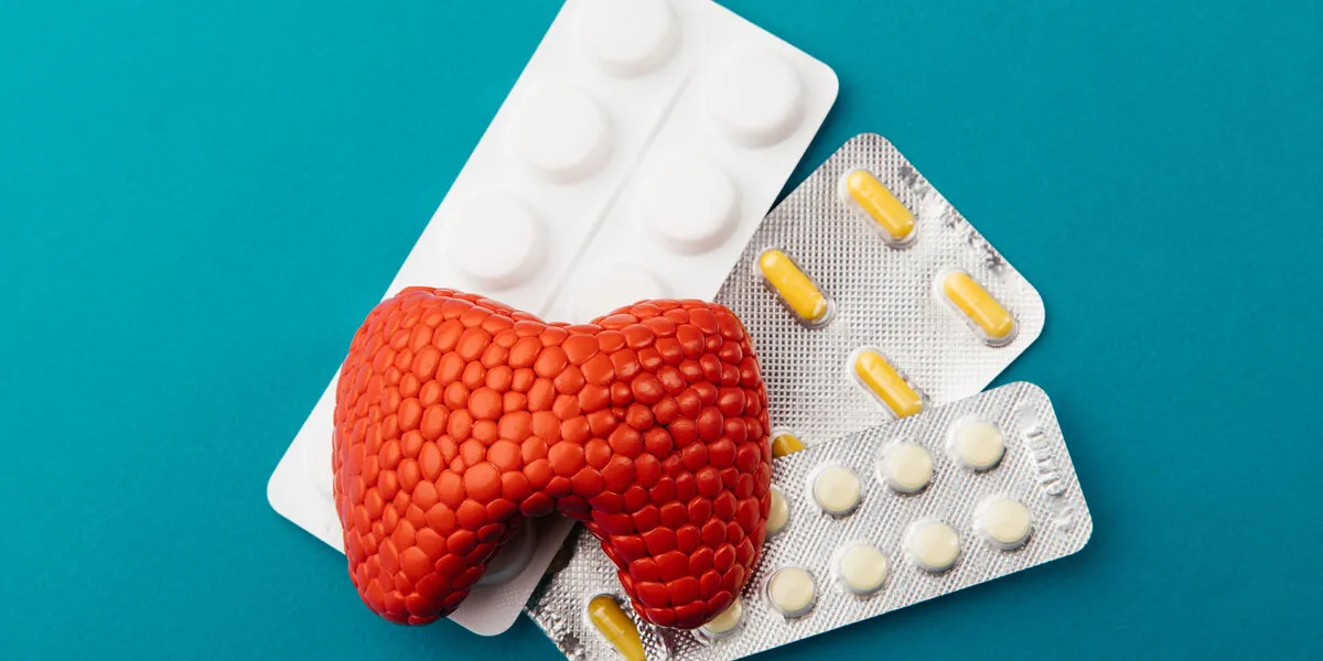 model of thyroid and pills on a blue background, top view