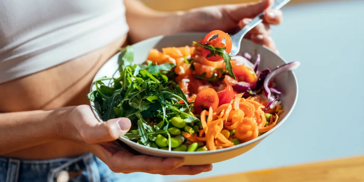 shot of fitness woman eating a healthy poke bowl in the kitchen at home