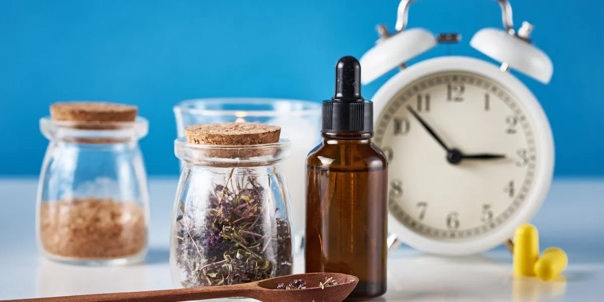 herbal medicine for treat depression and insomnia concept alarm clock, medicine herbs and aromatherapy oil on blue background