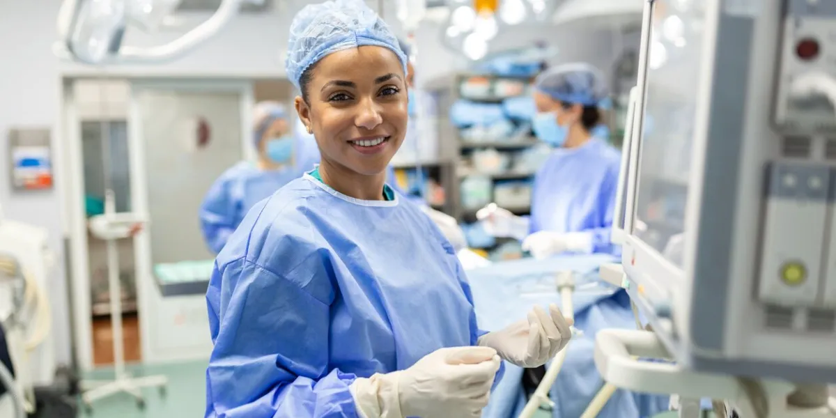 anesthesiologist checking monitors while sedating patient before surgical procedure in hospital operating room young adult female african american patient is asleep on operating table during surgery