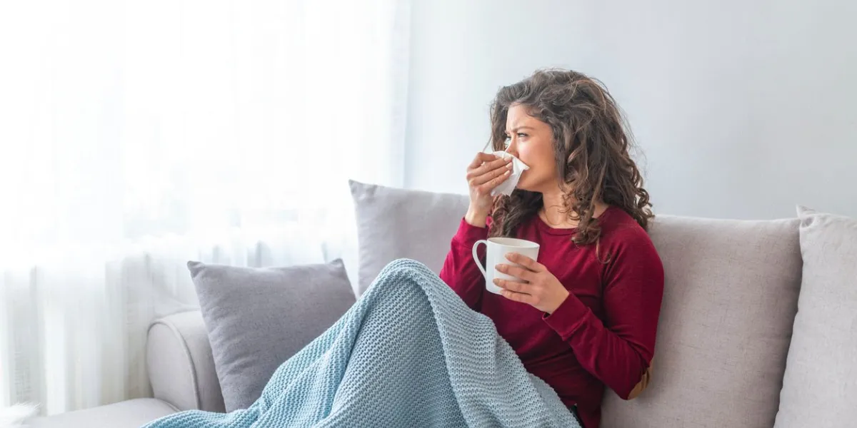 sick desperate woman has flu rhinitis, cold, sickness, allergy concept pretty sick woman has runnning nose, rubs nose with handkerchief sneezing female brunette sneezing in a tissue