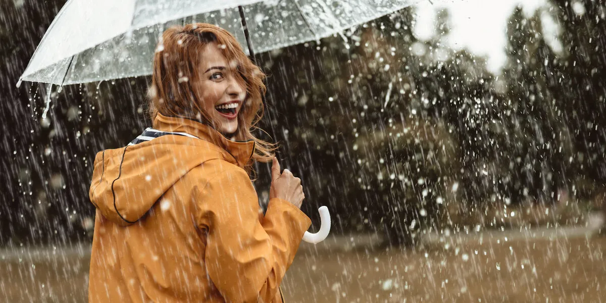 cheerful pretty girl holding umbrella while strolling outside she is turning back and looking at camera with true delight and sincere smile copy space in right side