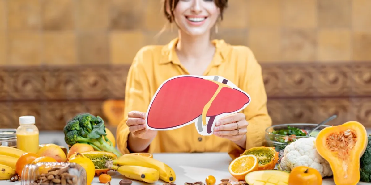 woman holding human liver model with variety of healthy fresh food on the table concept of balanced nutrition for liver health