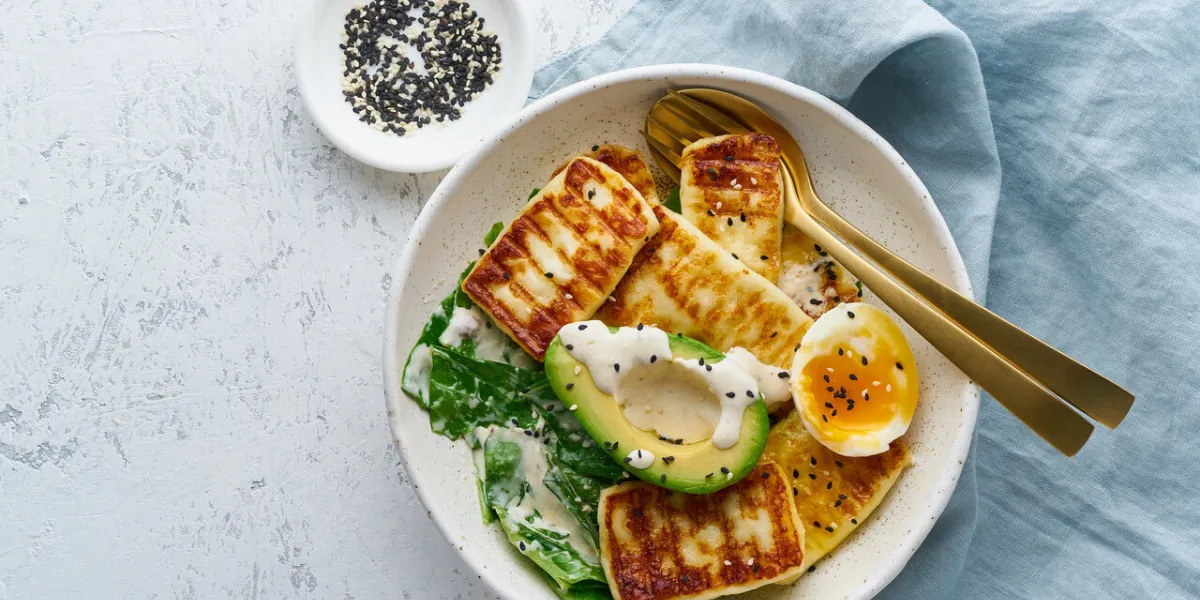 keto ketogenic diet soft boiled eggs with grilled haloumi, avocado and lettuce, mediterranean cuisine on pastel background
