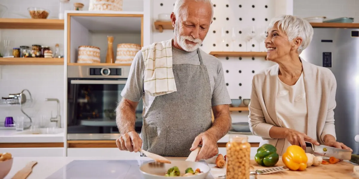 an elderly couple having fun in the kitchen preparing healthy food