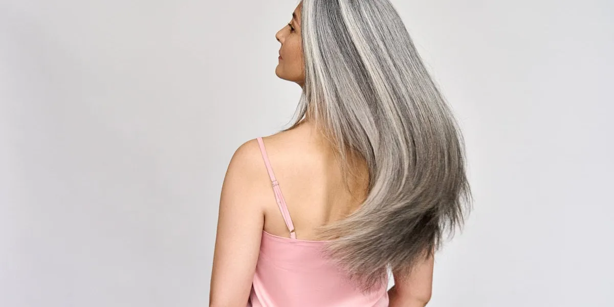 back view of senior mature middle aged older asian lady with long gray natural coloring vibrant silky hair dry hair replenishing healing treatment for women after menopause advertising concept