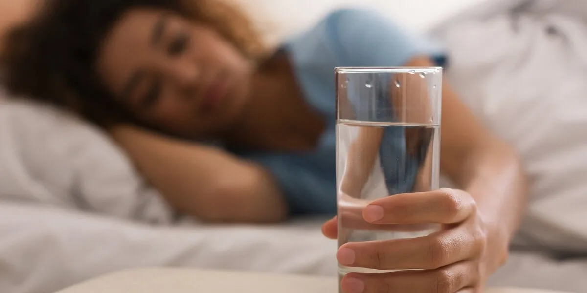 woman's hand taking glass of water, waking up in the morning