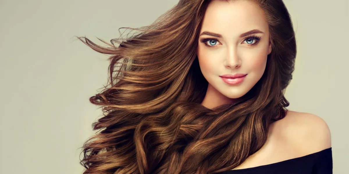 young, brown haired woman with voluminous hairbeautiful model with long, dense, curly hairstyle and vivid makeup perfect dense, wavy,and shiny hair hairdressing art, hair care and beauty products