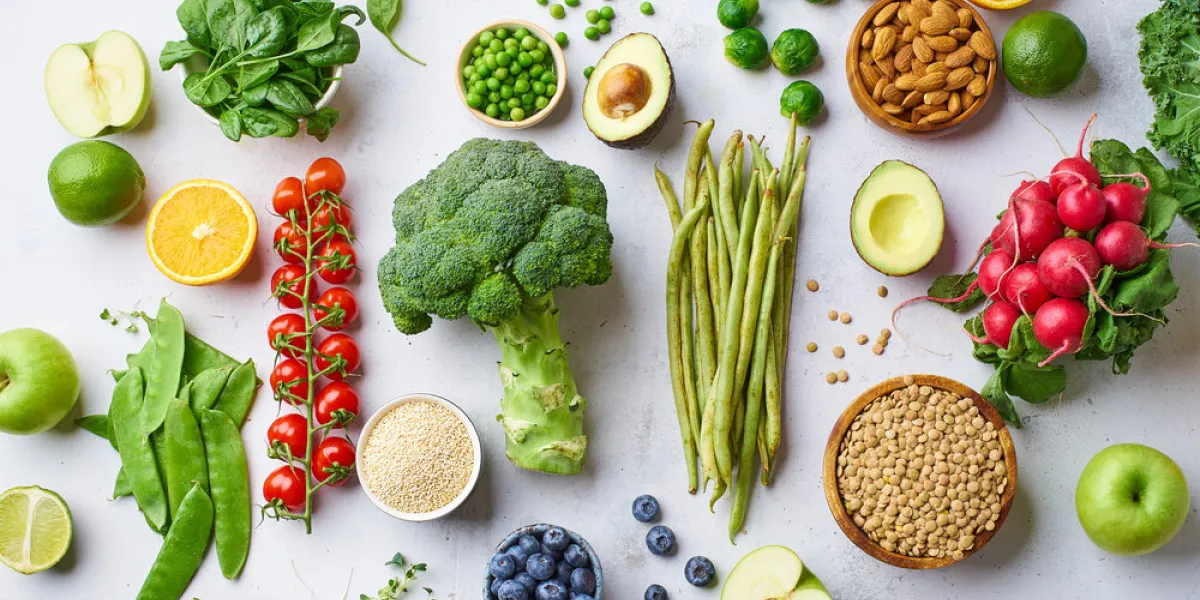 creative flat lay with healthy vegetarian meal ingredients raw food concept a variety of organic fruits, nuts, berries and vegetables with avocado vegan menu