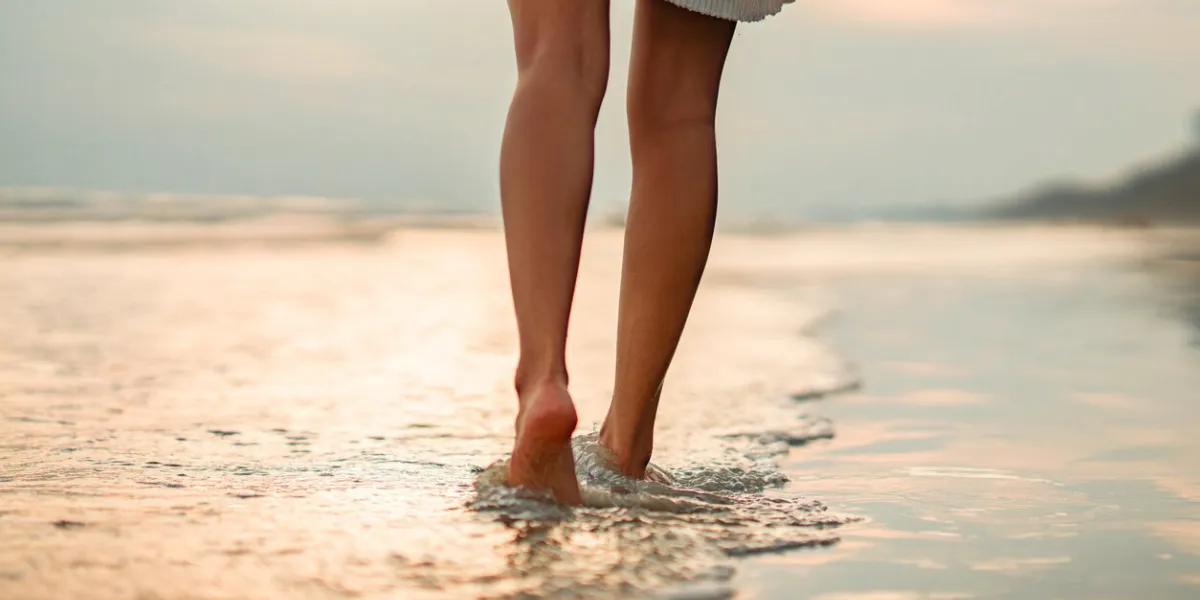 closeup of woman feet walking on sand beach during a golden hour sunset travel and relaxing in summer