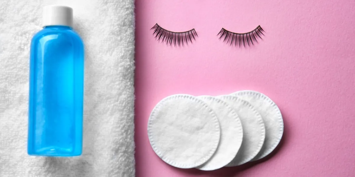 makeup remover, false eyelashes and cotton pads on color background