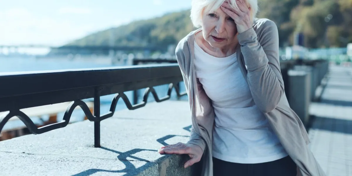 need to take my pills exhausted older lady leaning on a barrier and touching her forehead while suffering from a terrible headache outdoors