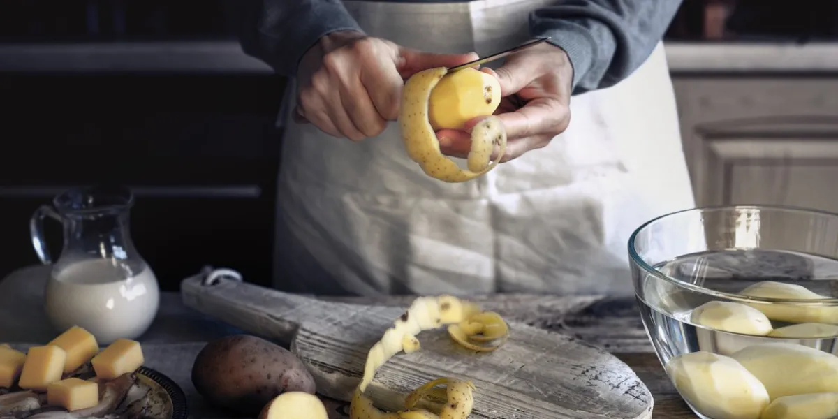woman peel potatoes on the wooden table horizontal