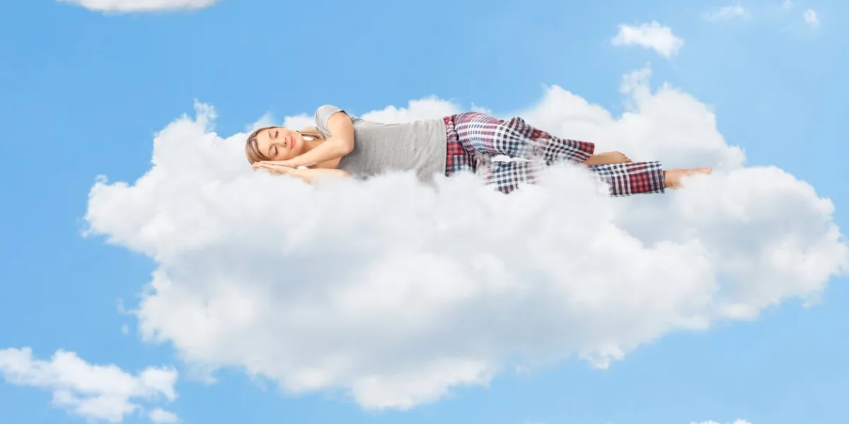 tranquil scene of a young woman dreaming and sleeping on a cloud up in the sky