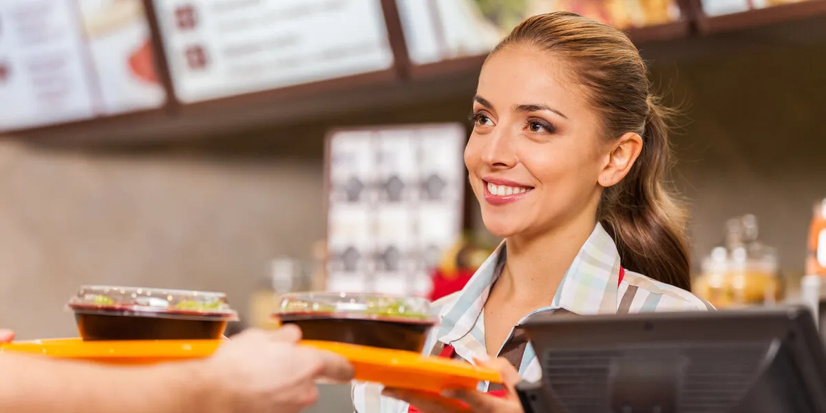 restaurant worker serving two fast food meals with smile woman holding tray with salads at fast food restaurant