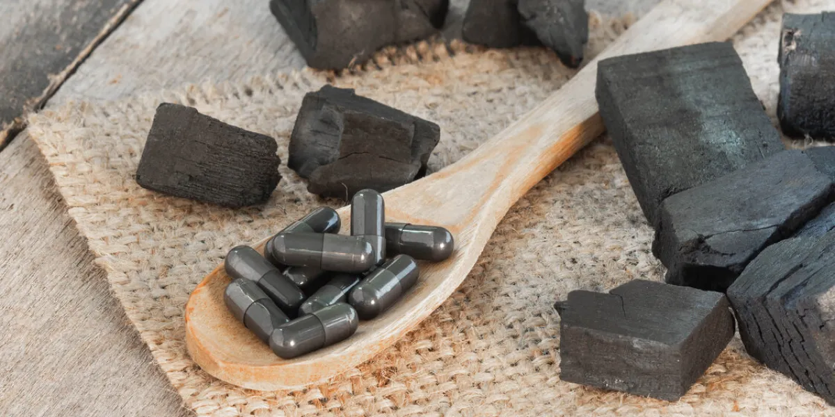 charcoal and charcoal capsule on hemp sack with wood background