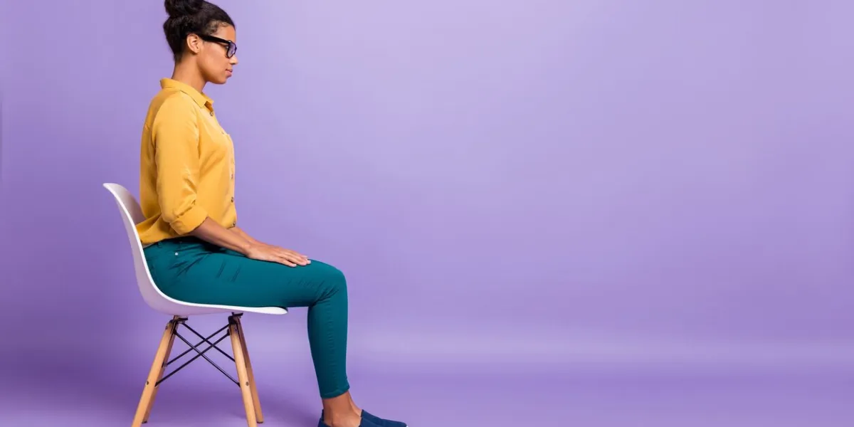 full length profile photo of pretty dark skin lady on chair look empty, space listen employer question interview wear specs yellow shirt trousers isolated purple color background