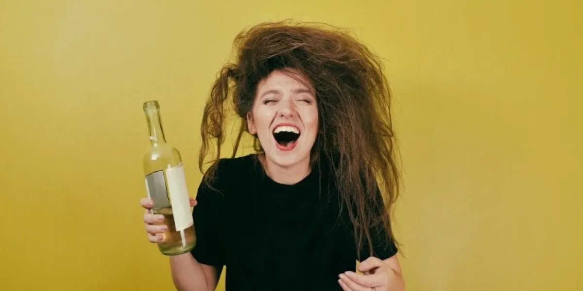 drunk girl with a bottle of wine on a yellow background