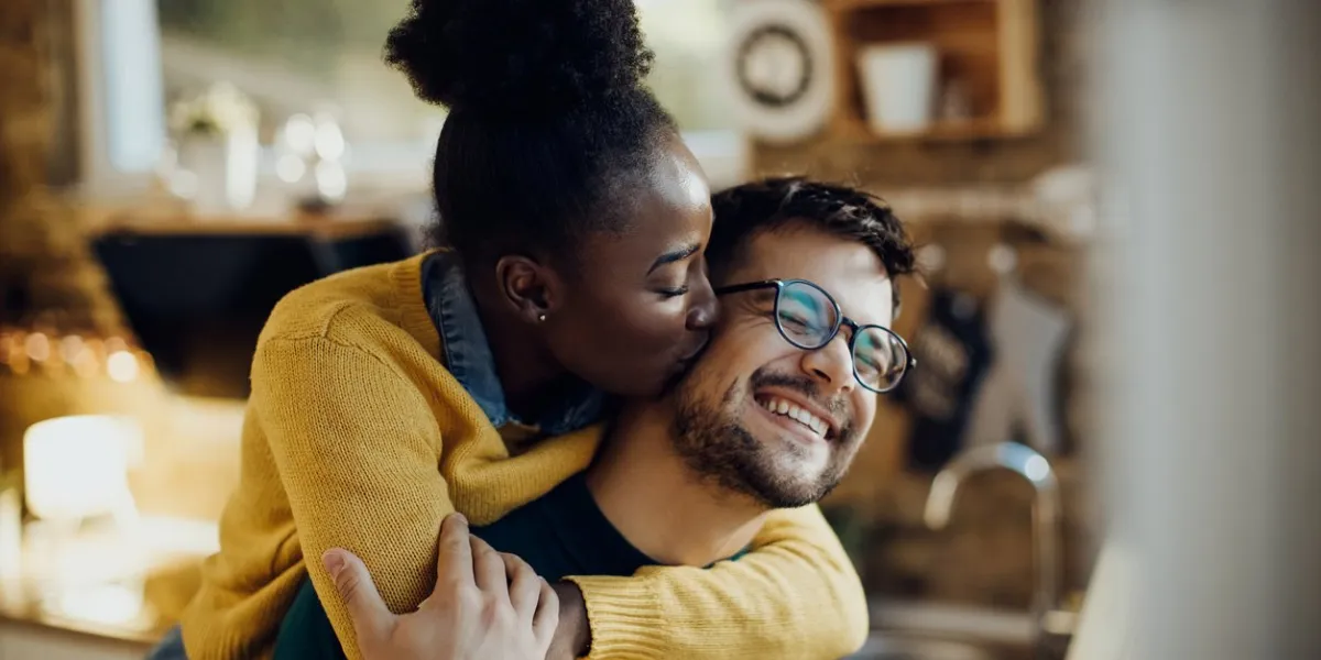 young african american woman kissing her boyfriend having fun with him at home