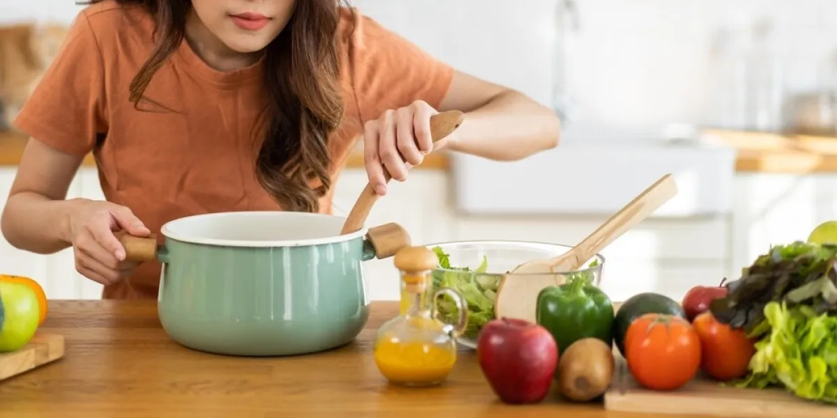 young,woman,standing,near,stove,and,cooking,,housewife,,meal,,chef