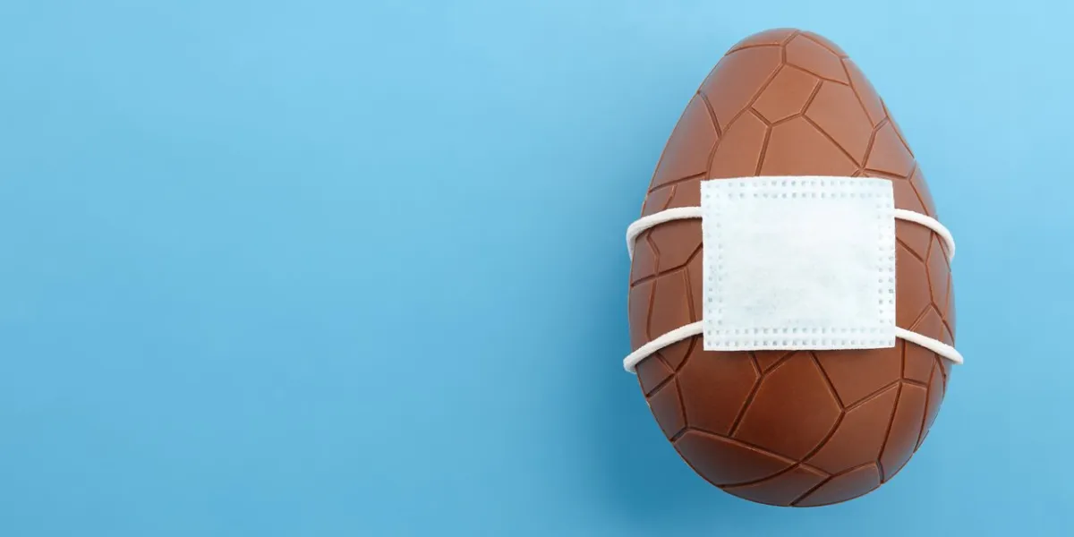 chocolate easter egg with corona virus mask, creative holiday concept