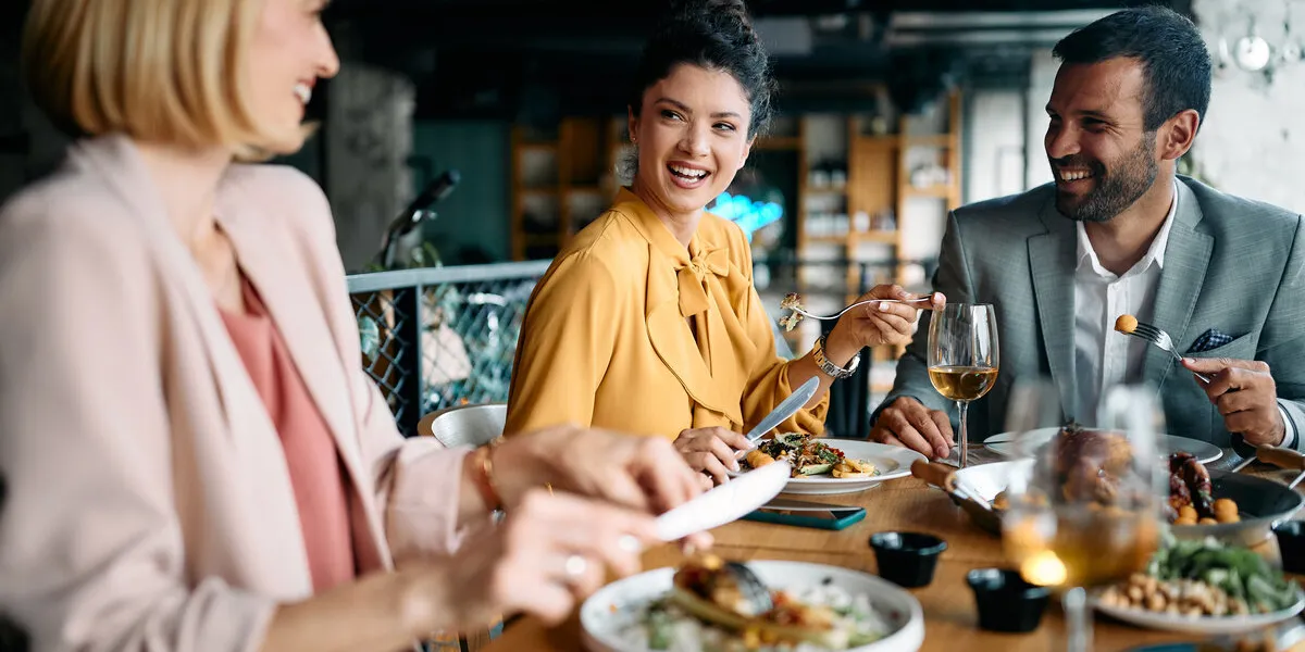 happy entrepreneur talks to her coworkers during business lunch in restaurant