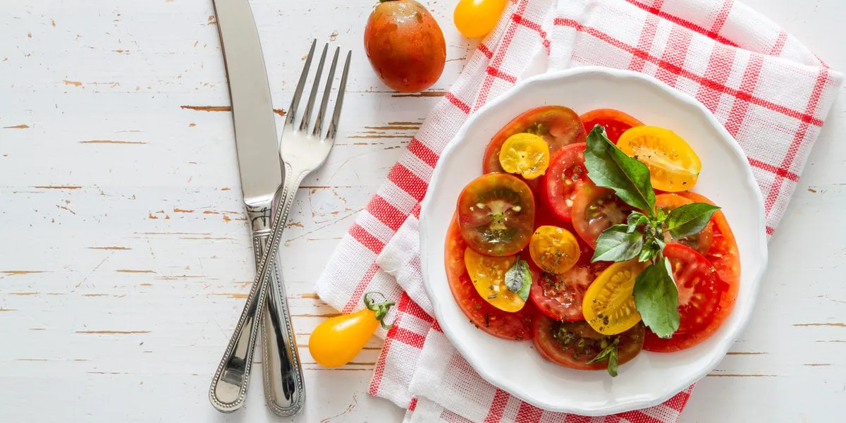 colorful tomato salad basil white plate on rustic wood background