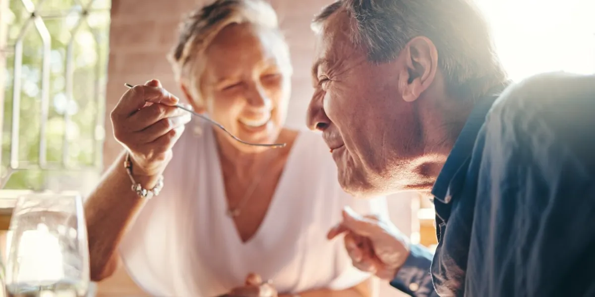 couple, love and food with a senior man and woman on a date in a restaurant while eating on holiday travel, romance and dating with an elderly male and female pensioner enjoying a meal together