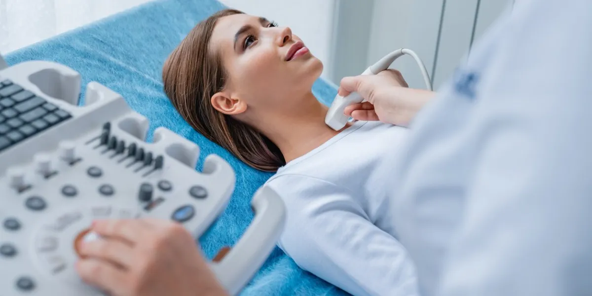 woman getting her neck examined by female doctor using ultrasound scanner at modern clinic
