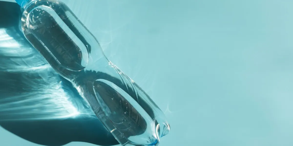 bottle of water with reflecting shadows lying on blue background healthy food concept top view copy space