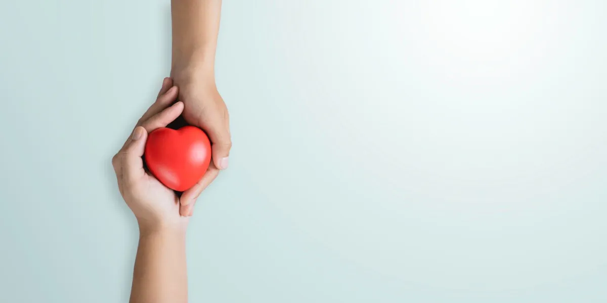 top view of hands holding red heart in concept healthcare, wellbeing, organ donation, and insurance life world heart day world health day national organ donor day on a blue background