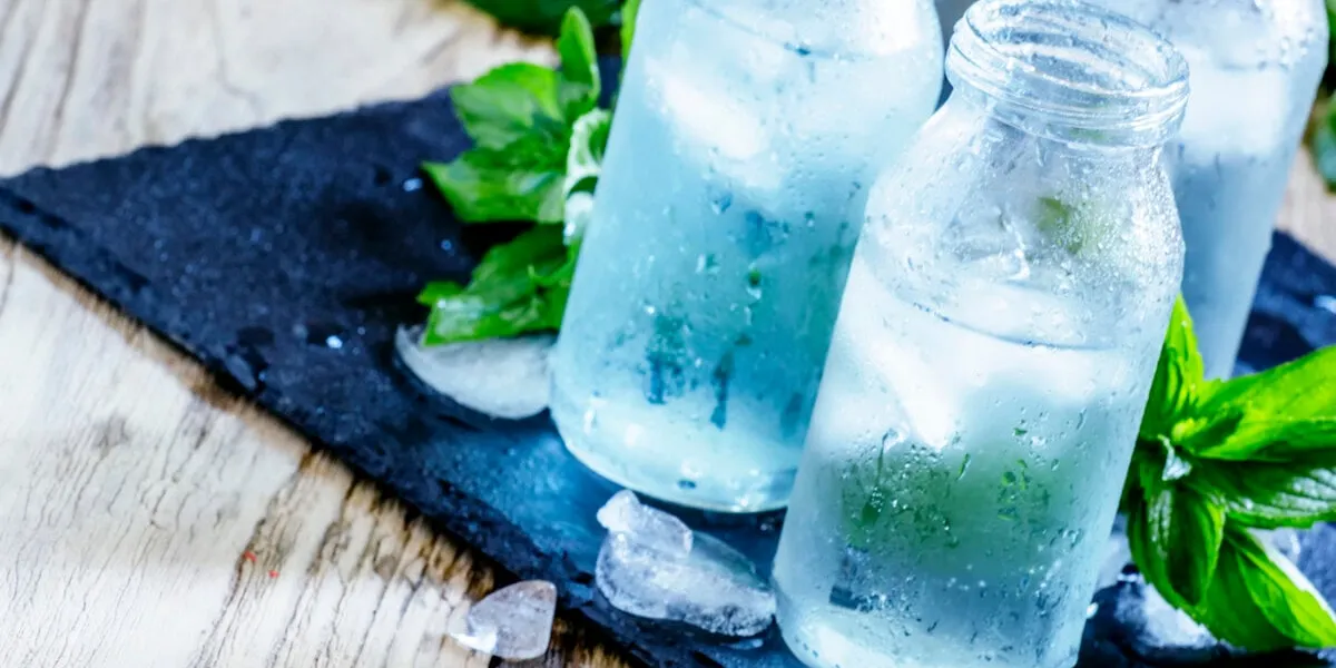 very cold mineral water with ice in a misted glass bottles, dark background, selective focus