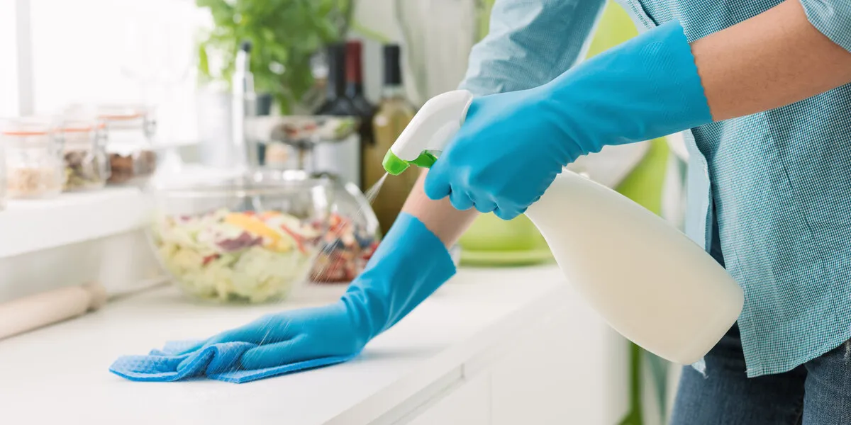 woman cleaning and polishing the kitchen worktop with a spray detergent, housekeeping and hygiene concept