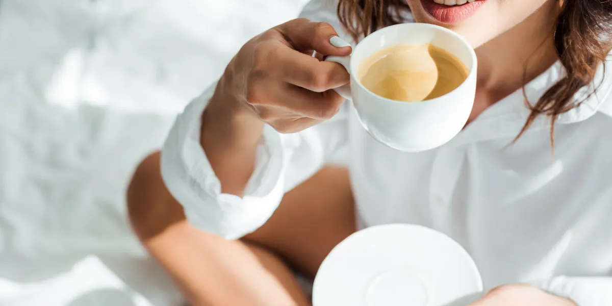 cropped view of woman drinking coffee from cup at morning