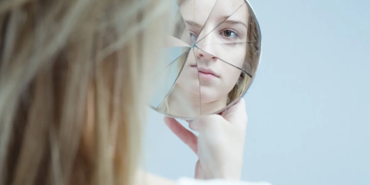 image of woman with mental disorder holding broken mirror