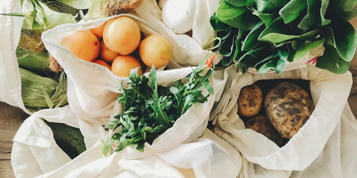 fresh vegetables in eco cotton bags on table in the kitchen lettuce, corn, potatoes, apricots, bananas, rucola, mushrooms from market zero waste shopping concept  ban plastic