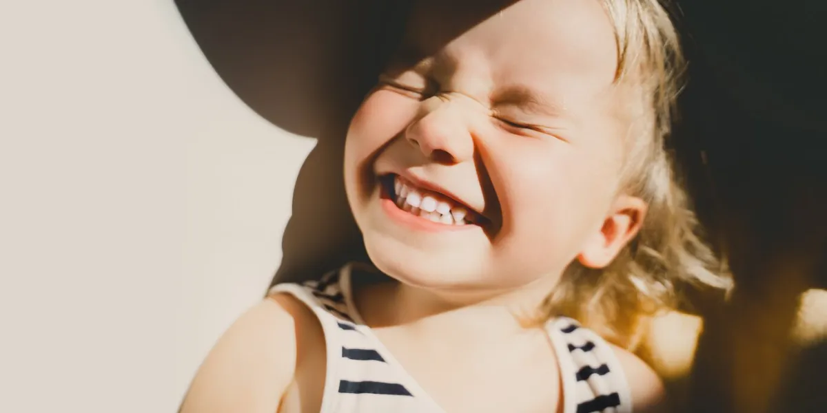cutest little girl smiling and squinting in sunlight happy toddler having fun portrait of playful child preschool age lifestyle photography