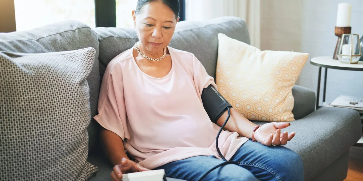 blood pressure, healthcare and senior woman in living room with equipment for hypertension sick, illness and elderly female person in retirement with medical tool in the lounge of modern home