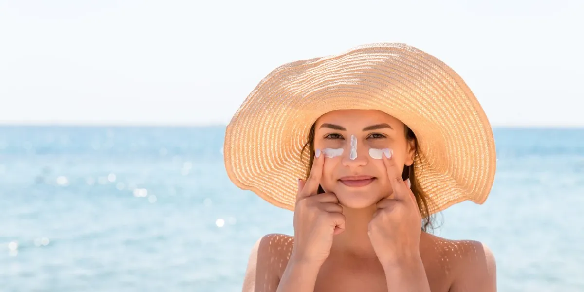 pretty woman protects her skin on face with sunblock at the beach