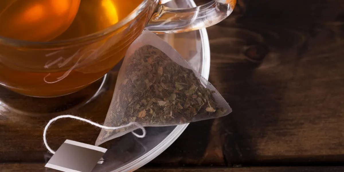 tasse de thé frais avec soucoupe et sachet de thé bouchent ensemble sur une table en bois sombre avec un espace pour le texte