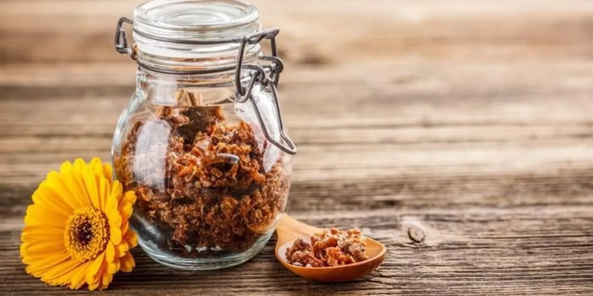granule de propolis en pot de verre sur fond en bois rustique