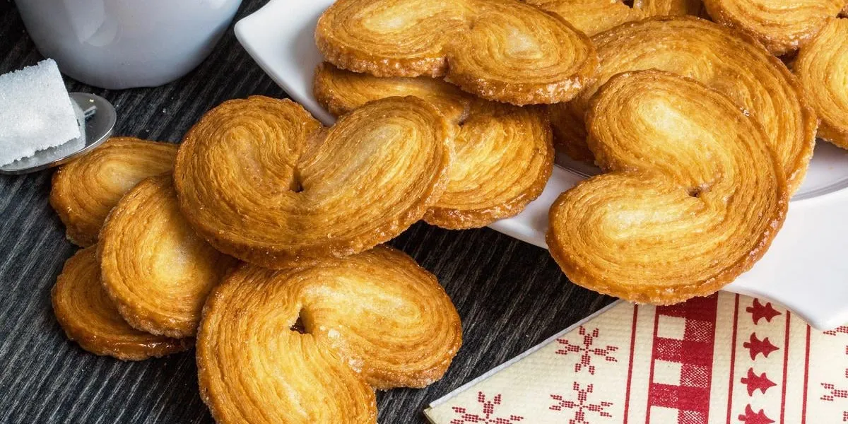gateaux palmiers sur fond sombre avec tasse et sucre