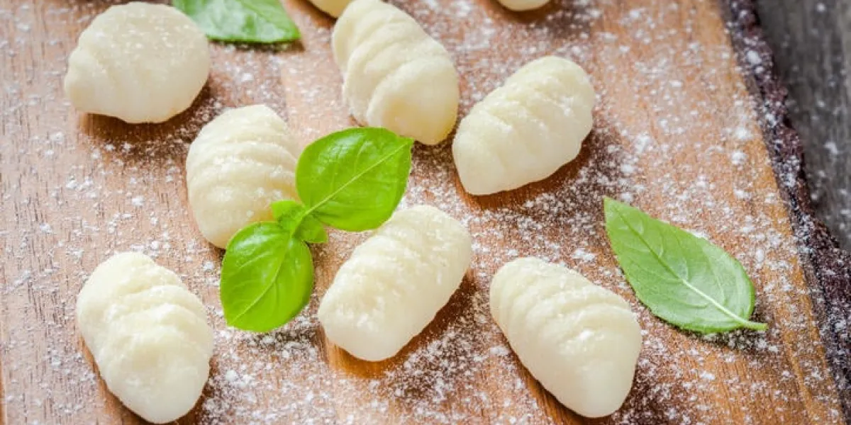 gnocchi cru fait maison avec de la farine et du basilic frais closeup sur une planche à découper en bois