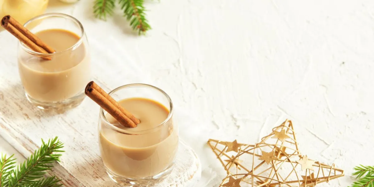 lait de poule avec des bâtons de cannelle, décoration de noël et ornements sur fond blanc - boisson festive de noël alcoolisée maison, cocktail